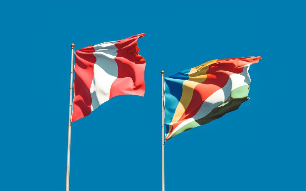 Two colorful national flags waving against a vibrant blue sky.